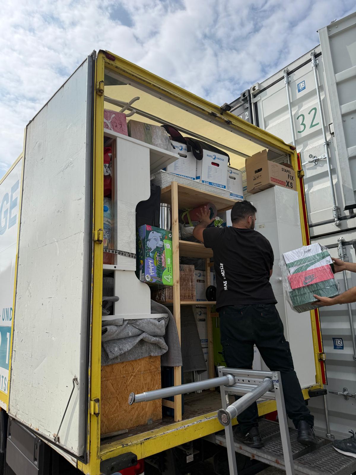 Mitarbeiter von Mars Umzüge verstaut Umzugskartons für die Einlagerung im Container